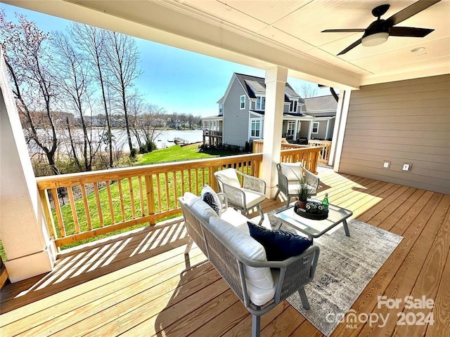 deck with an outdoor living space, a water view, and ceiling fan