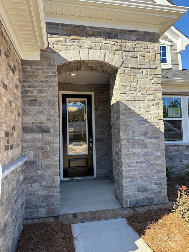 property entrance with brick siding, stone siding, and a shingled roof