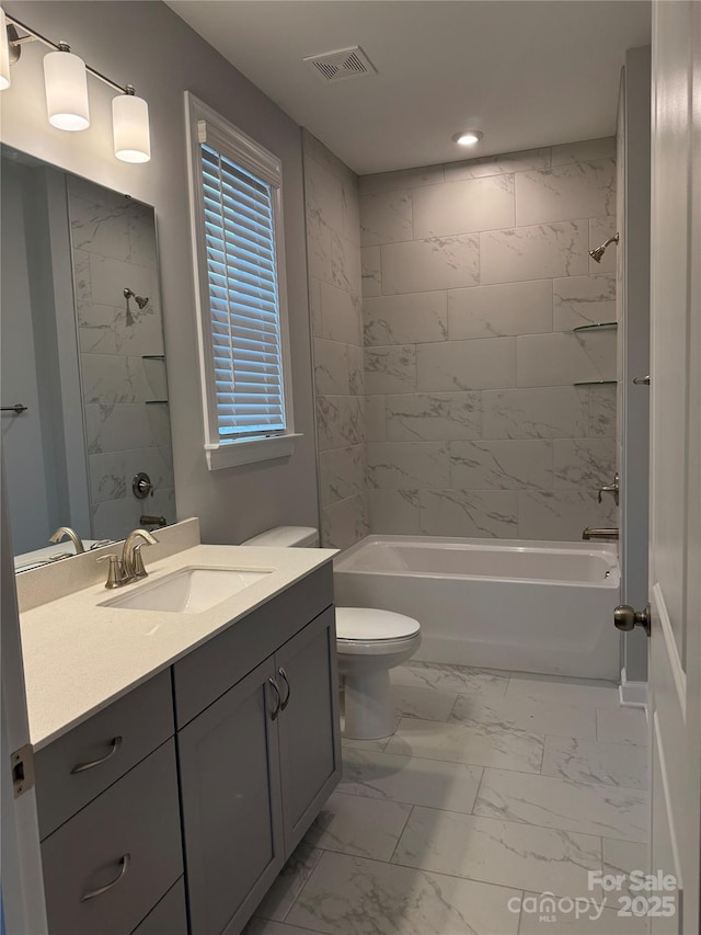 full bathroom with tiled shower / bath, vanity, and toilet