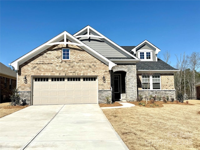 craftsman-style house with stone siding, a garage, brick siding, and driveway