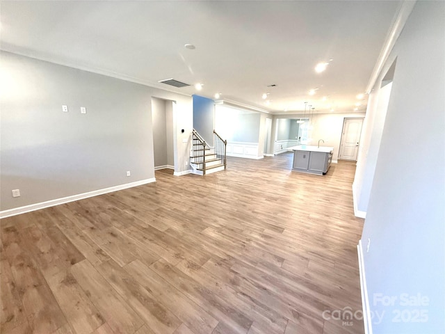 basement featuring visible vents, light wood-style flooring, stairway, and crown molding