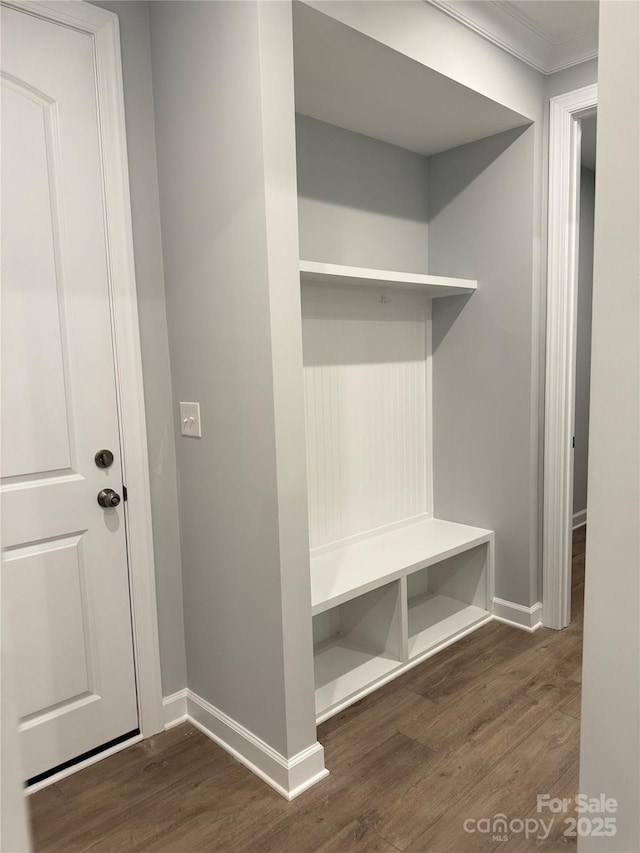 mudroom featuring crown molding, baseboards, and dark wood-style flooring