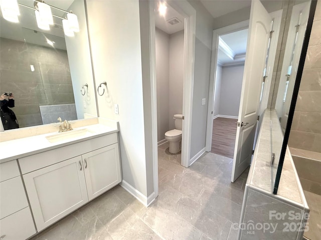 full bath featuring baseboards, toilet, vanity, and a tile shower