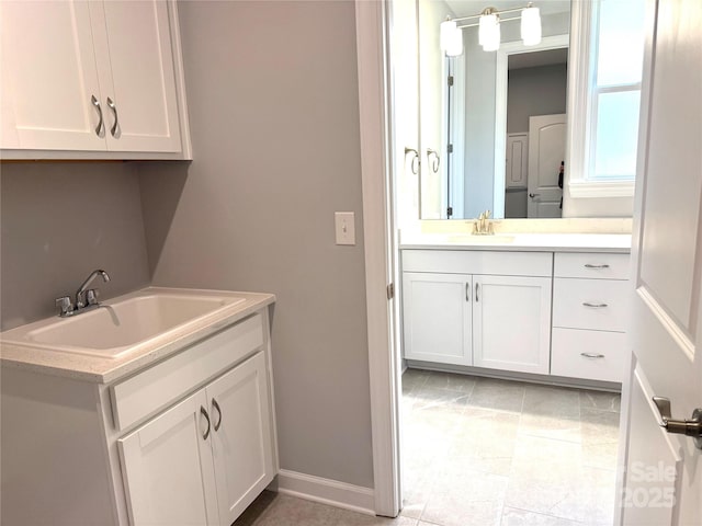 laundry room featuring light tile patterned flooring, baseboards, and a sink