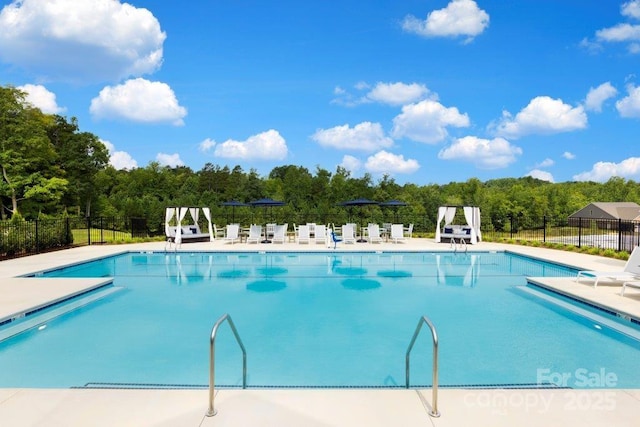 community pool with a patio area and fence