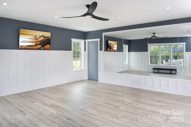 unfurnished living room with plenty of natural light, recessed lighting, a wainscoted wall, and wood finished floors