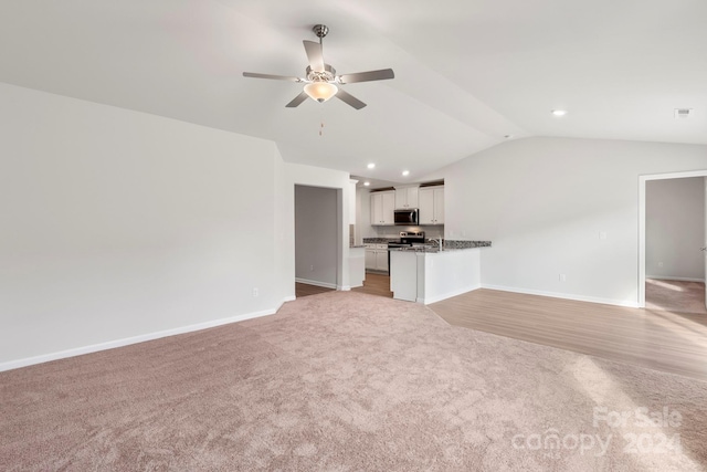 unfurnished living room with ceiling fan, light colored carpet, and vaulted ceiling