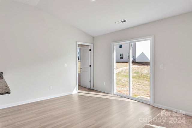 spare room featuring lofted ceiling, light wood-type flooring, and a wealth of natural light