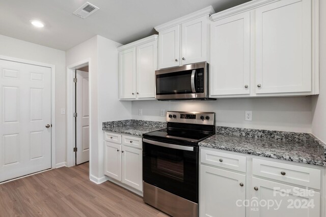 kitchen featuring white cabinets, light stone countertops, light wood-type flooring, and stainless steel appliances