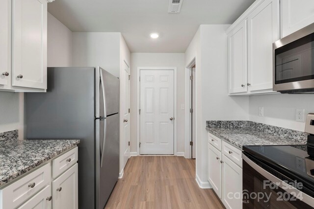 kitchen featuring white cabinets, appliances with stainless steel finishes, and light hardwood / wood-style flooring