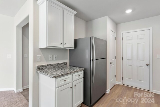 kitchen featuring stainless steel refrigerator, light hardwood / wood-style flooring, and white cabinets