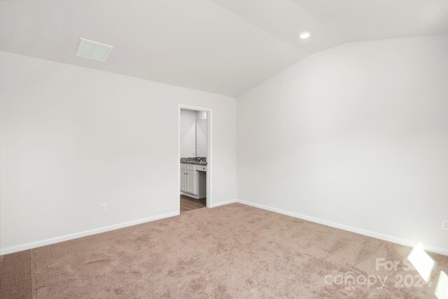 unfurnished bedroom with carpet, ensuite bathroom, and lofted ceiling