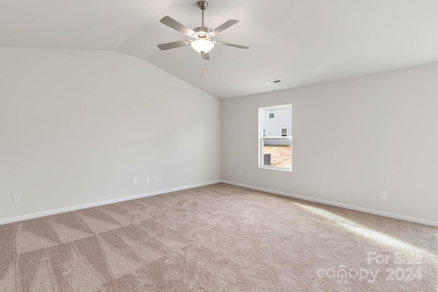 unfurnished room with vaulted ceiling, light colored carpet, and ceiling fan