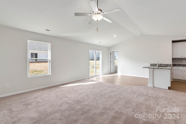 unfurnished living room with light carpet, visible vents, a ceiling fan, and lofted ceiling