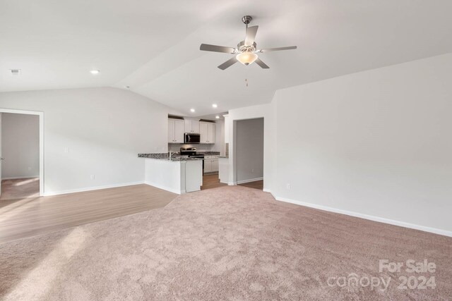 unfurnished living room with a ceiling fan, light colored carpet, vaulted ceiling, and baseboards