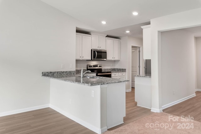 kitchen featuring recessed lighting, appliances with stainless steel finishes, light wood-style floors, white cabinetry, and light stone countertops