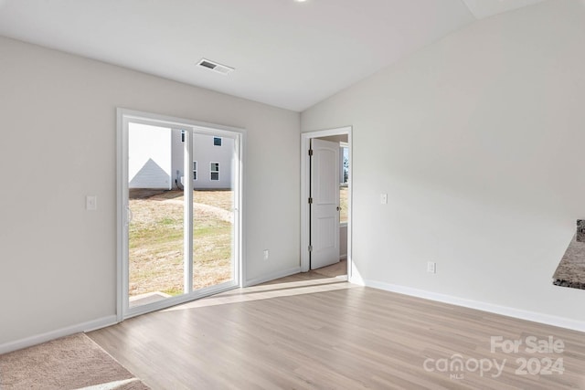 empty room with lofted ceiling, light wood-style flooring, visible vents, and baseboards