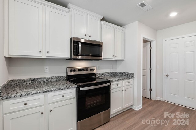 kitchen with white cabinetry, light hardwood / wood-style flooring, light stone counters, and stainless steel appliances