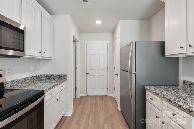 kitchen with light wood-type flooring, white cabinetry, light stone counters, and stainless steel appliances