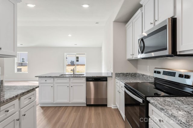 kitchen with white cabinetry, light hardwood / wood-style flooring, sink, light stone countertops, and appliances with stainless steel finishes