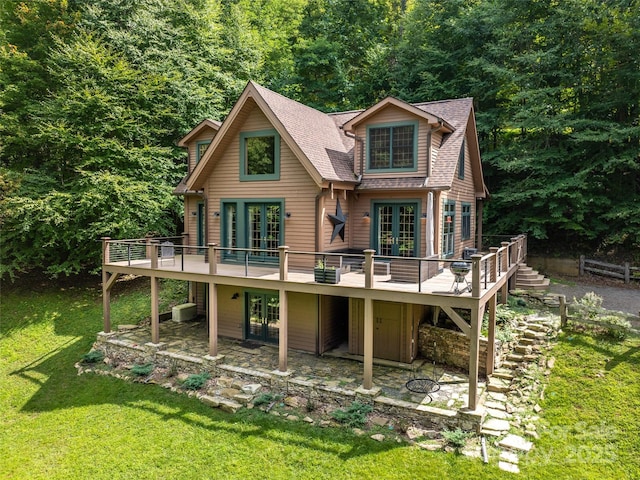 rear view of property with french doors, a deck, a patio, and a lawn