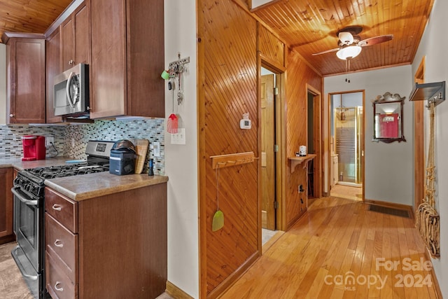 kitchen featuring light wood finished floors, stainless steel appliances, a ceiling fan, tasteful backsplash, and wood ceiling