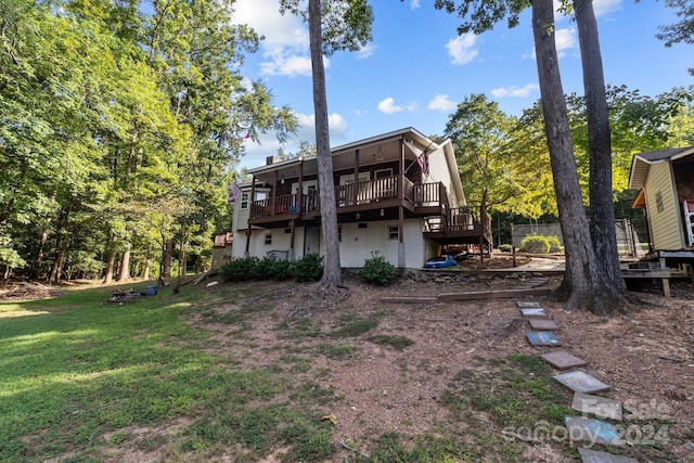 rear view of house featuring stucco siding, a deck, and a yard