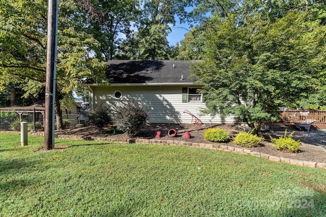 rear view of property featuring fence and a yard