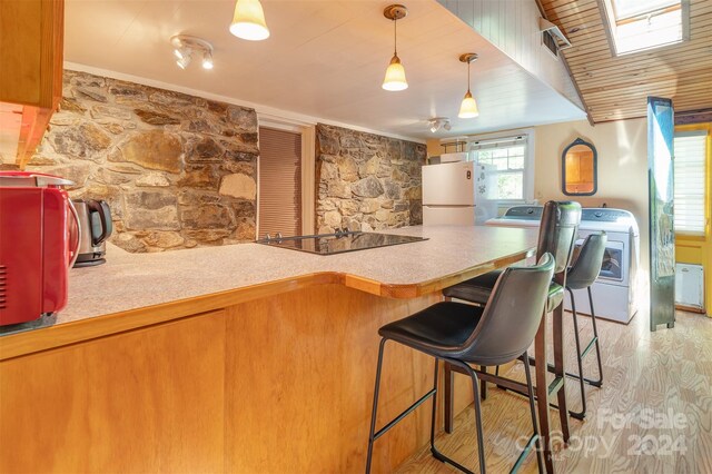 kitchen with white refrigerator, a skylight, wood-type flooring, and hanging light fixtures