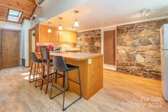 kitchen with light hardwood / wood-style floors, a breakfast bar, hanging light fixtures, kitchen peninsula, and a skylight