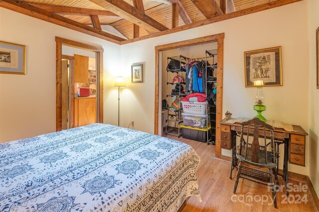 bedroom with wood ceiling, a closet, light wood-type flooring, and vaulted ceiling with beams