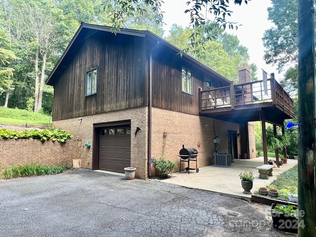 view of home's exterior with a garage, brick siding, central AC unit, and aphalt driveway