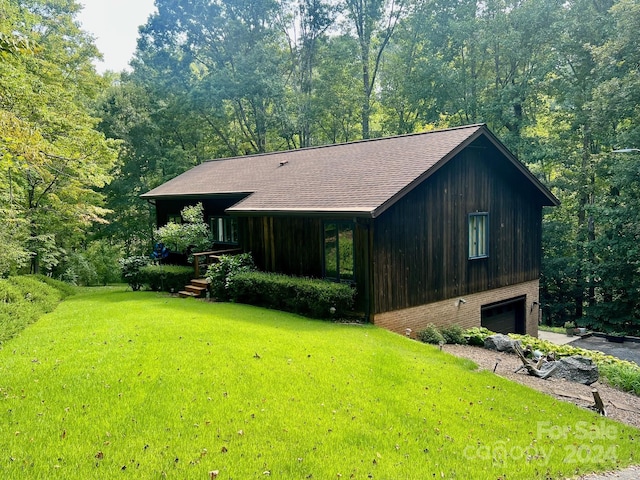 view of side of property with brick siding, a yard, a view of trees, and an attached garage