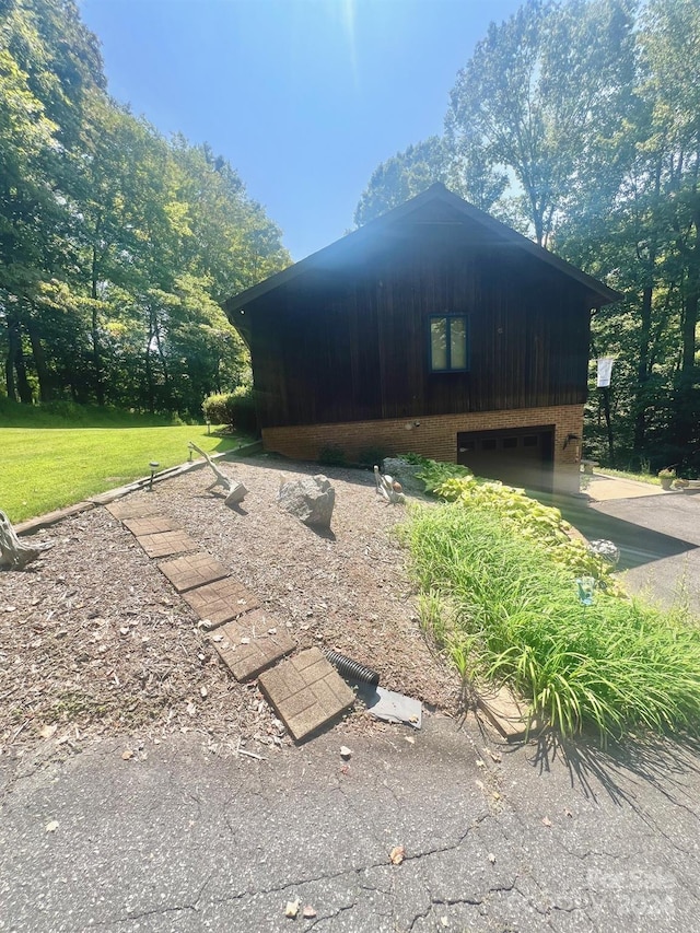 view of side of home with a garage, a lawn, and brick siding