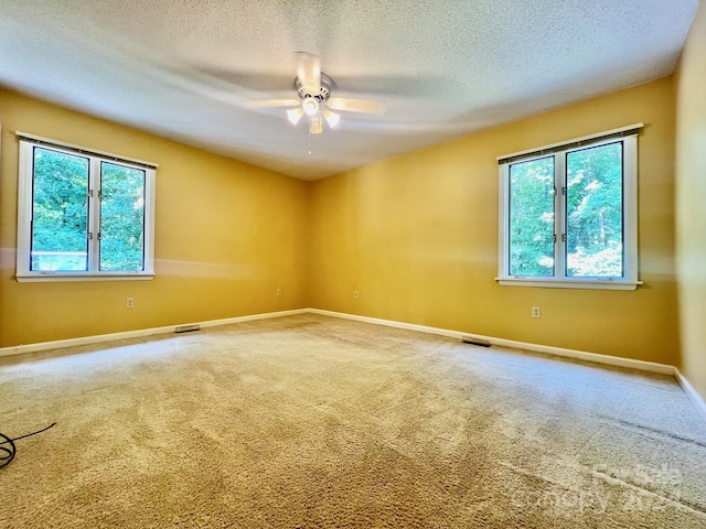 carpeted empty room with visible vents, ceiling fan, a textured ceiling, and baseboards