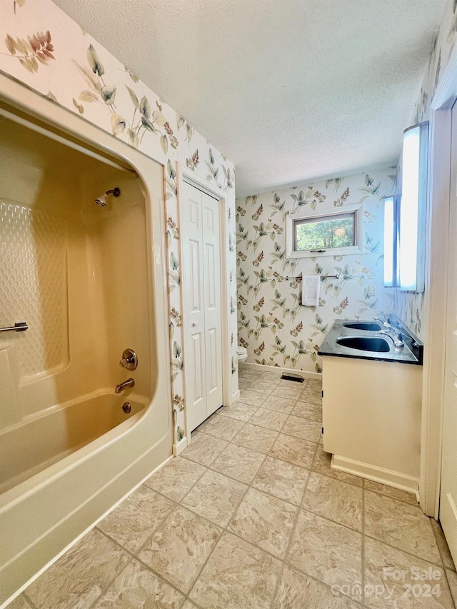 full bath with a textured ceiling, toilet, bathing tub / shower combination, vanity, and wallpapered walls