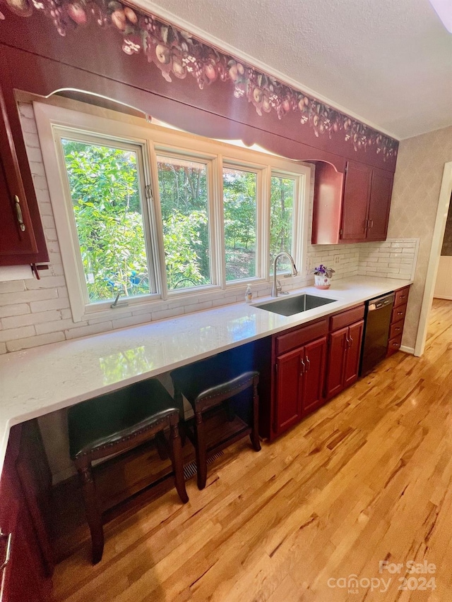 kitchen featuring black dishwasher, light wood-style flooring, a sink, and light countertops