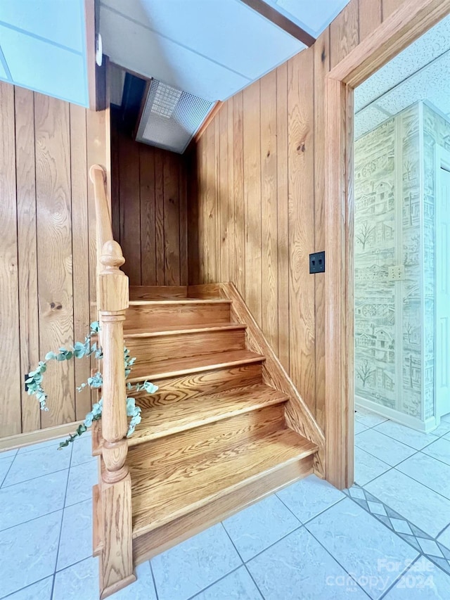 stairway with tile patterned flooring and wooden walls