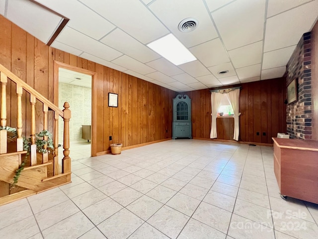 interior space with stairs, light tile patterned flooring, visible vents, and wooden walls