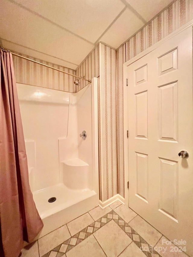 bathroom with a shower with shower curtain, tile patterned floors, and wallpapered walls