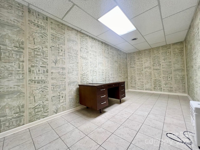 unfurnished office with a paneled ceiling, light tile patterned floors, baseboards, and wallpapered walls