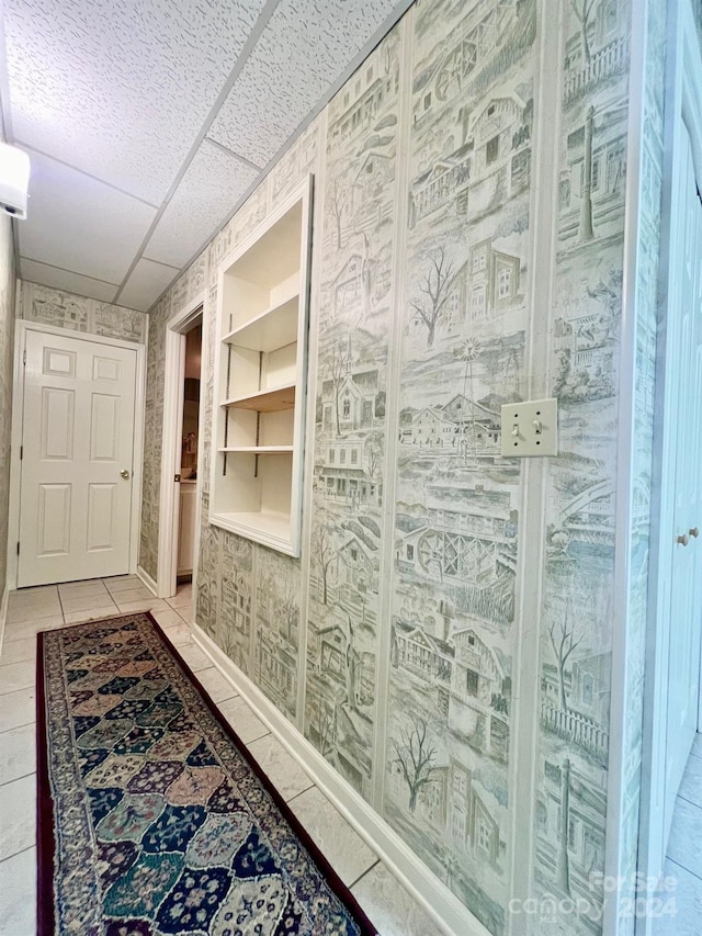 hallway featuring light tile patterned floors and a drop ceiling