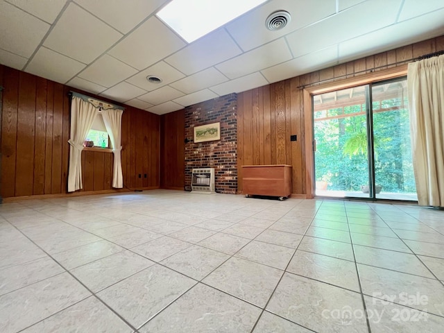 unfurnished living room with a healthy amount of sunlight, visible vents, wooden walls, and light tile patterned flooring