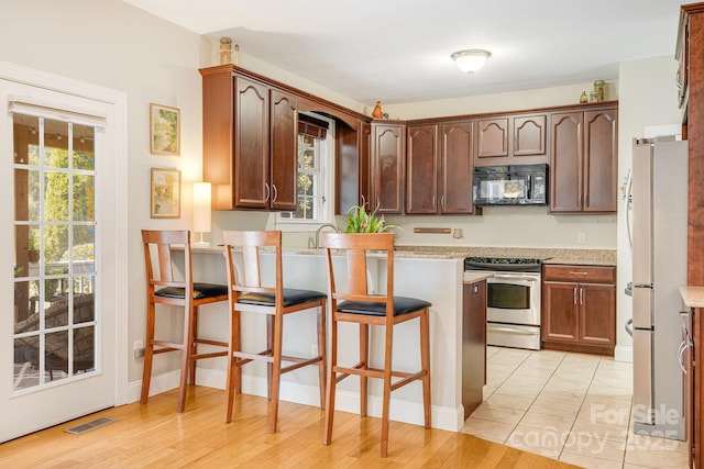 600 Vista Falls Rd, Mills River, NC 28759 - kitchen featuring stainless steel range, black microwave, freestanding refrigerator, a peninsula, and a breakfast bar