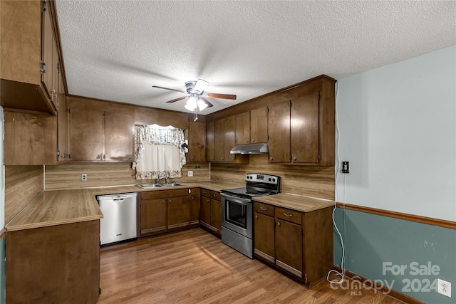 kitchen featuring a textured ceiling, appliances with stainless steel finishes, sink, ceiling fan, and light wood-type flooring