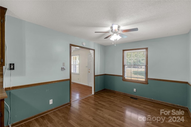 spare room featuring a wealth of natural light, hardwood / wood-style floors, and ceiling fan