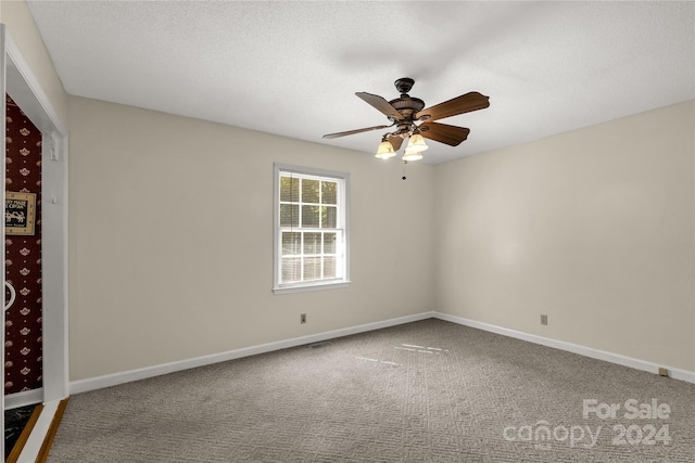 carpeted spare room featuring a textured ceiling and ceiling fan