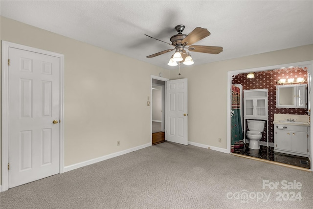 unfurnished bedroom featuring carpet flooring, ceiling fan, sink, and ensuite bath