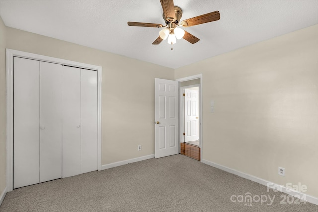 unfurnished bedroom with a textured ceiling, carpet flooring, ceiling fan, and a closet