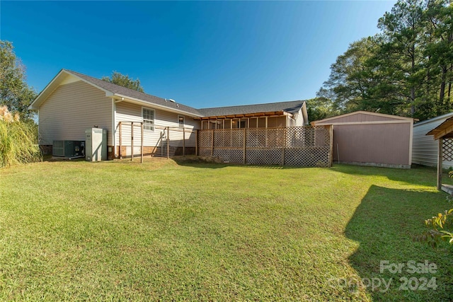 rear view of property with a yard, a shed, and central air condition unit